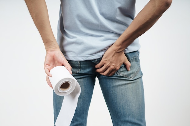 Young Man holding his bottom and tissue paper because Diarrhea, Hemorrhoids, constipation. Health care and medical concept.