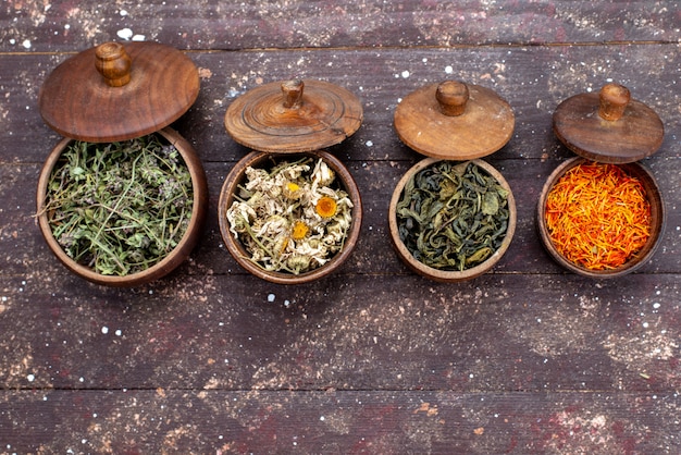 A top view dried seasonings different colored inside bowls on the brown background green mint dry