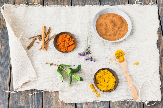 Spices near cinnamon and plant twig on textile on table 