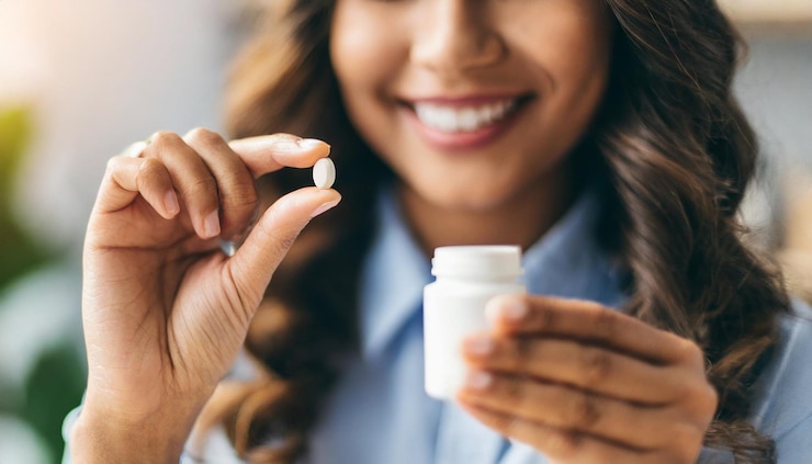 womans hands delicately extracting a pill from a bottle reflecting health and wellness choices