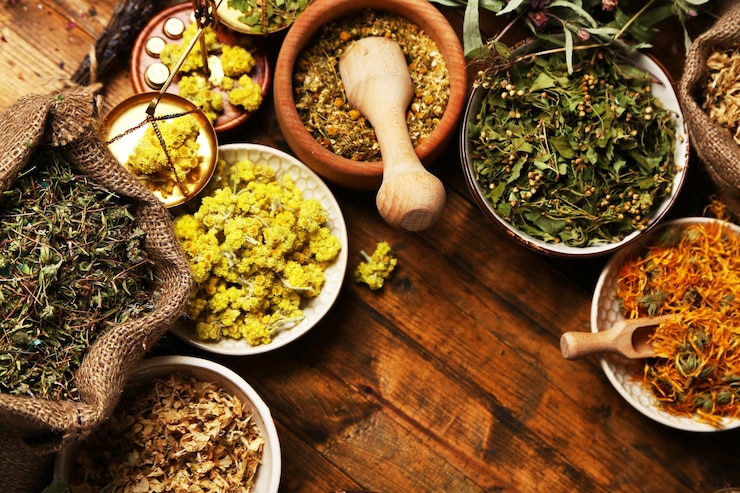 Assortment of dry medicinal herbs in bowls on wooden background top view