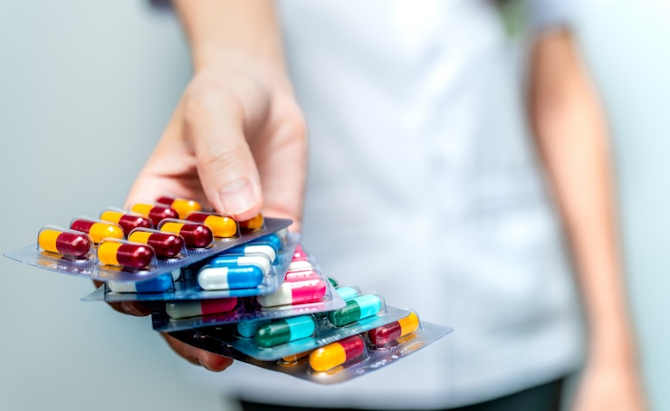Pharmacist or doctor hand holding pack of antibiotic capsule pills and giving patient or people. Antibiotic drug overuse. Antimicrobial drug resistance. Community pharmacist.
