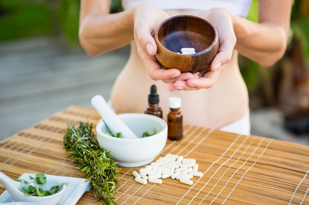Fit woman showing bowl of pills