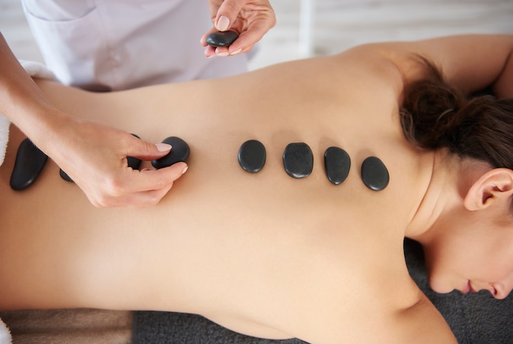 Woman getting massage of back by hot stones